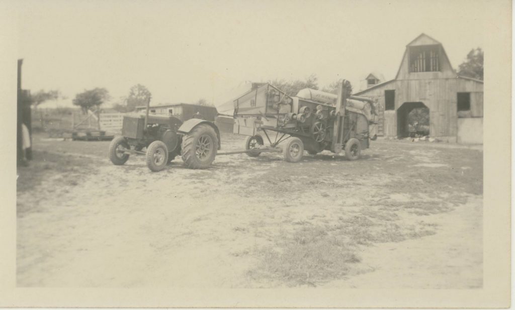Black and white photograph of an antique John Deere tractor and a Twin City Separator